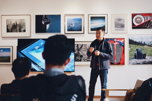 asian man in front of a wall of photographs for a workshop free marketing