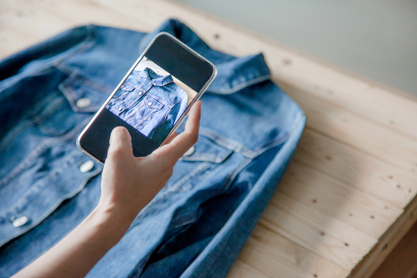 girl taking cell phone image of denim jacket for small business marketing