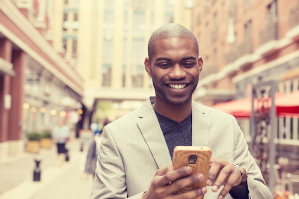 african american man smiling reading social media on his phone