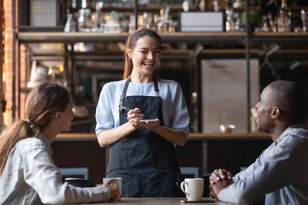 happy female server joking with cafe patrons for customer loyalty